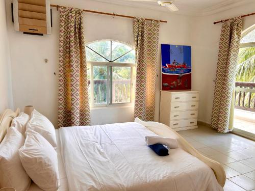 a bedroom with a white bed and a window at Hibiscus WhiteHouse in Brufut