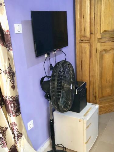 a fan sitting on a stand next to a television at Le Caire قاهرة in Rufisque