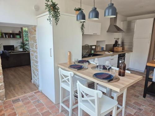 une cuisine avec une table et des chaises en bois ainsi qu'une cuisine avec des placards blancs dans l'établissement La maison de Pierre, studio à 20 min du Puy du Fou, à Mortagne-sur-Sèvre