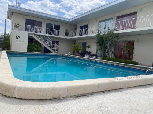 a large blue swimming pool in front of a building at Queens Lodge Motel in West Palm Beach