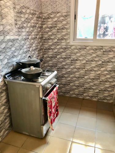 a kitchen with a stove with two pans on it at Le Caire قاهرة in Rufisque