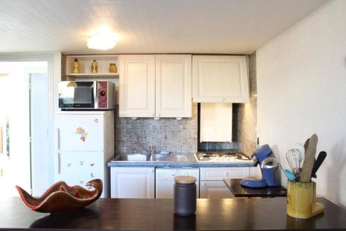 une cuisine avec des armoires blanches et une table en bois dans l'établissement Maison 4 pièces 8 couchages PORT LA NOUVELLE PN000-001, à Port-la-Nouvelle