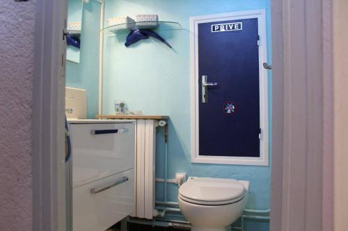La salle de bains est pourvue de toilettes et d'une porte bleue. dans l'établissement Maison 4 pièces 8 couchages PORT LA NOUVELLE PN000-001, à Port-la-Nouvelle