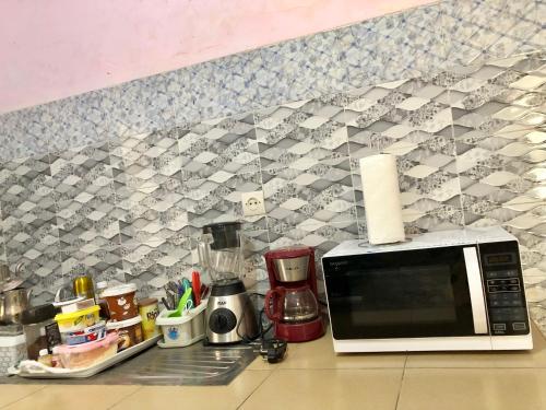 a kitchen counter with a microwave and a tile wall at Le Caire قاهرة in Rufisque