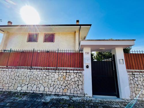 a house with a red gate and a stone fence at Alba Chiara Sperlonga in Sperlonga