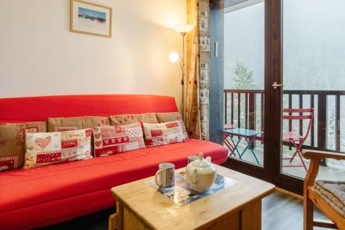 - un canapé rouge dans le salon avec une table dans l'établissement Le Petit Bonheur, à Modane