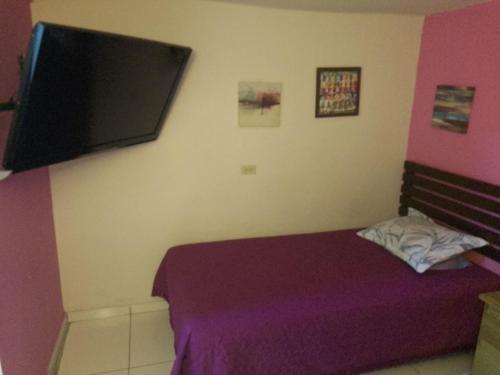 a bedroom with a purple bed and a flat screen tv at Comfort Home Escalón in San Salvador