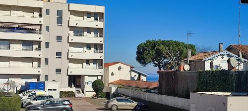 un grand bâtiment blanc avec des voitures garées dans un parking dans l'établissement Résidence la Croisette Arcachon, à Arcachon