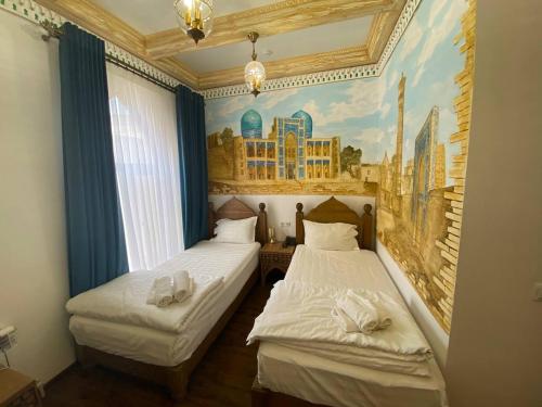 two beds in a room with a painting on the wall at Xadijam boutique hotel in Bukhara