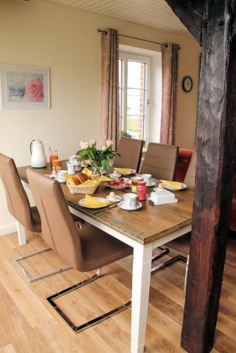 a dining room table with chairs and food on it at Rose in Fehmarn