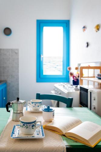a table with an open book and two cups and a book at Grazioso Bilocale fronte mare in Santa Lucia