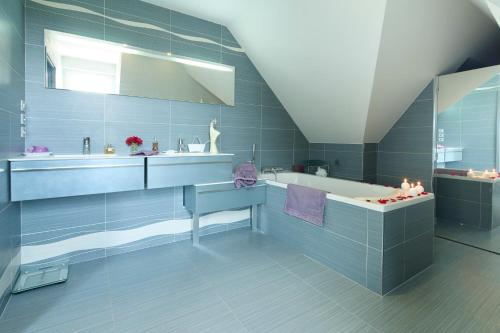 een blauwe badkamer met een bad en een wastafel bij Rivoli in Pornichet