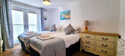 1 Schlafzimmer mit 2 Betten, einer Kommode und einem Fenster in der Unterkunft No 1 Oceans in Perranporth