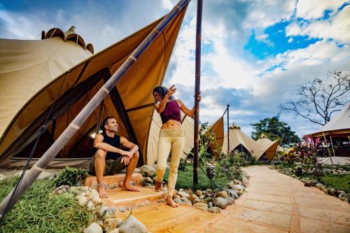 a man and a woman standing next to a tent at Eco Luxe Glamping Nest #5 - 2 Queen Beds at Holos in Barú