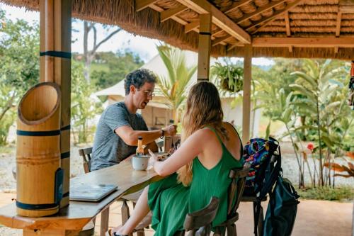 a man and a woman sitting at a table at Eco Luxe Glamping Nest #2 - 2 Queen Beds at Holos in Barú