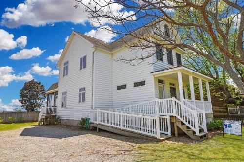 a white house with a front porch and a tree at Herbie's Hideaway - Water views & Screened porch! in Black Point Landing