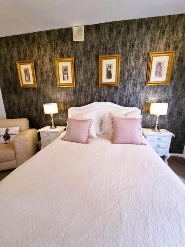 a bedroom with a large white bed with pink pillows at Station Cottage Hawes in Hawes