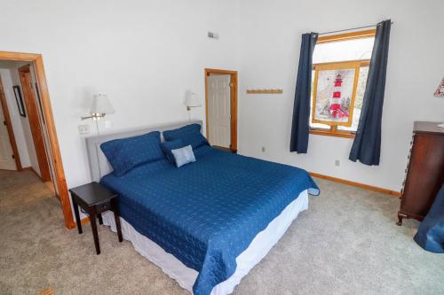 a bedroom with a blue bed and a window at Herbie's Hideaway - Water views & Screened porch! in Black Point Landing