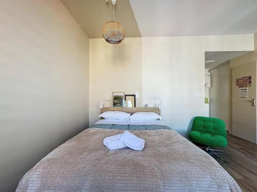 une chambre avec un grand lit et une chaise verte dans l'établissement Studio Chaleureux et Lumineux - Centre Clermont Blatin B, à Clermont-Ferrand