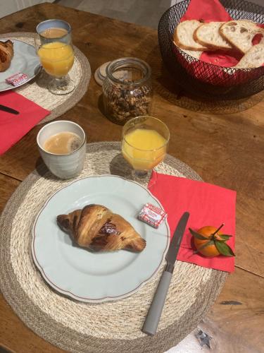 einen Tisch mit einem Teller Brot und Orangensaft in der Unterkunft La Chambre du Clos - Meursault in Meursault