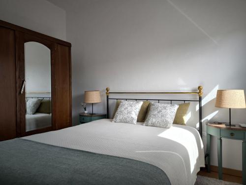 a bedroom with a bed with two lamps and a mirror at Casa do Pedro, Quinta Vale de Vila in São João da Pesqueira