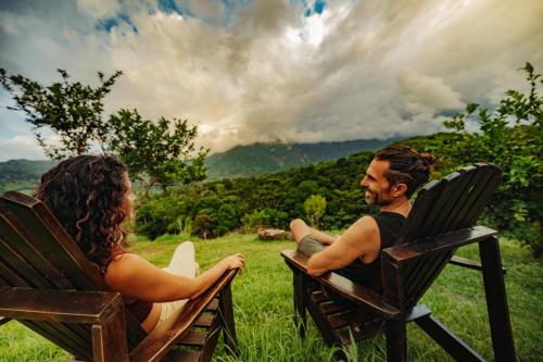 a man and a woman sitting in chairs in a field at Eco Luxe Glamping Nest #12 - King Bed at Holos in Barú