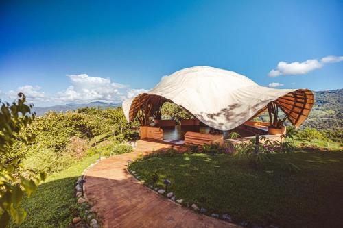 a house with a tent on top of a field at Eco Luxe Glamping Nest #12 - King Bed at Holos in Barú