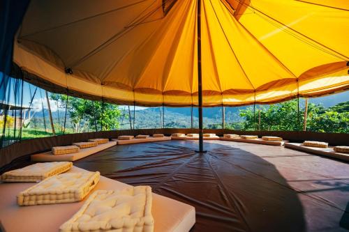 a stage with a large yellow umbrella and chairs at Eco Luxe Glamping Nest #12 - King Bed at Holos in Barú