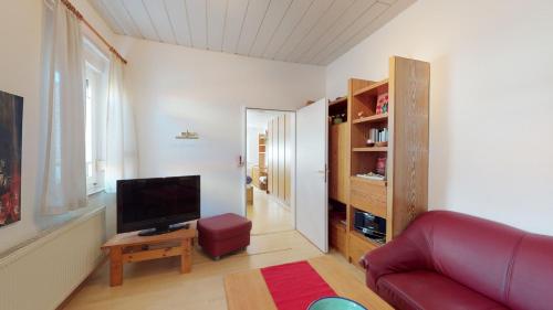 a living room with a red couch and a television at Strandhöhle in Borkum
