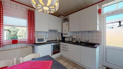 a kitchen with white cabinets and a table and a window at Strandhöhle in Borkum