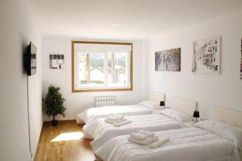 a room with four white beds and a window at Pensión A Solaina in O Pedrouzo