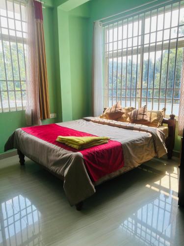 a large bed in a room with windows at Coorg Sana Riverside in Suntikoppa