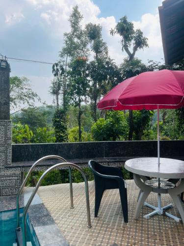 a table and chair with an umbrella on a balcony at Coorg Sana Riverside in Suntikoppa
