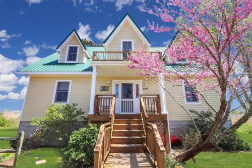 a house with a flowering tree in front of it at Heron's Cove on Salt Meadow - Pet friendly, waterfront home! in Deep Hole