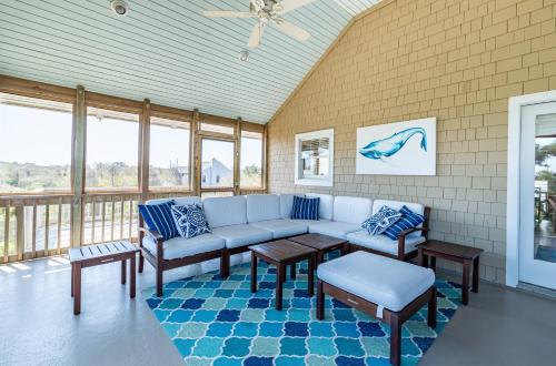 a living room with a couch and tables and windows at Shore Enough in Sanderling