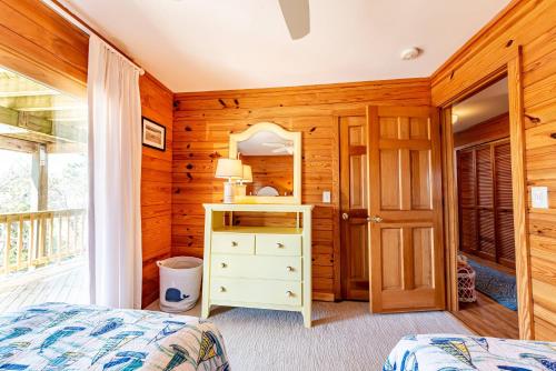 a bedroom with wooden walls and a bed and a mirror at Shore Enough in Sanderling