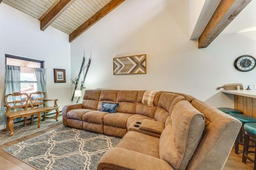 a living room with a brown couch and a table at Pet-Friendly Angel Fire Condo Walk to Ski Resort in Angel Fire
