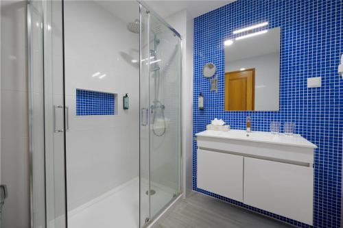 a blue tiled bathroom with a sink and a shower at Casa Azul 3 - Senhora da Rocha, Algarve in Porches