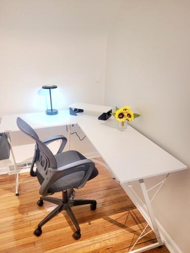 a white desk with a chair and a vase of flowers at Yellow Harmony in South Euclid