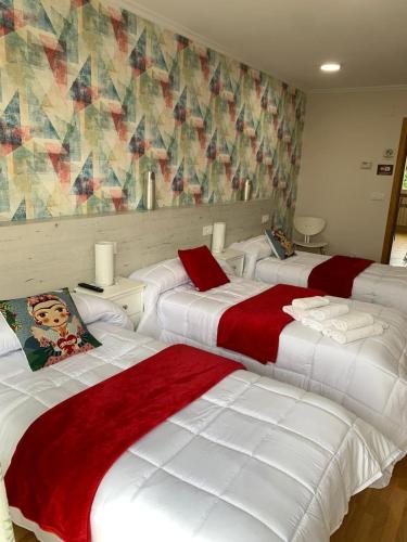 a bedroom with three beds with red and white sheets at Pensión A Solaina in O Pedrouzo