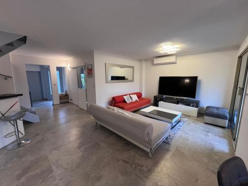 un salon avec un canapé et une télévision à écran plat dans l'établissement Villa Marina Cottage, à Mandelieu-la-Napoule