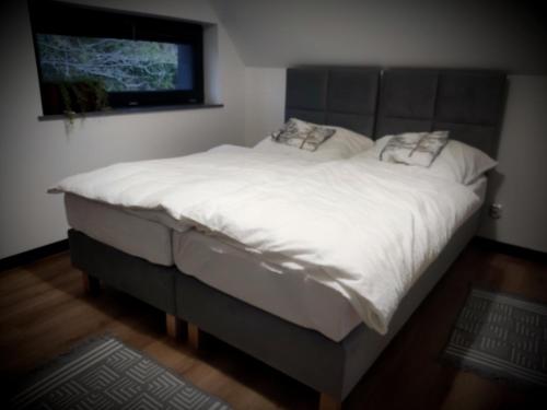 a large bed with white sheets and a tv on the wall at Nasza Baza wśród drzew prywatny dom z balią - jacuzzi Miedziana Góra Kielce świętokrzyskie in Ćmińsk