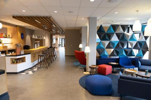 a lobby with blue and red chairs and a bar at Holiday Inn Express Caen Epron by IHG in Caen