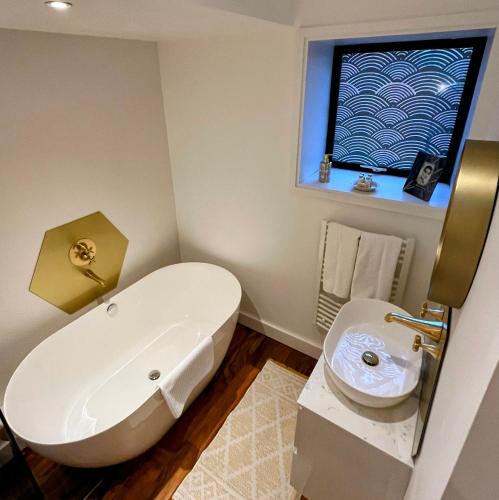 a bathroom with a white tub and a sink at New Forest Fordingbridge - Art Deco Unique Apartment in Fordingbridge