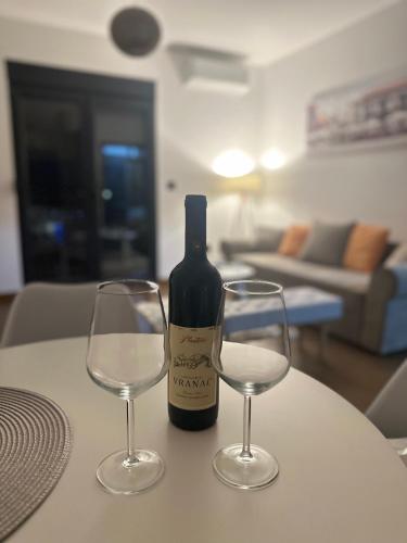 een fles wijn en twee wijnglazen op een tafel bij Hill Apartment in Podgorica