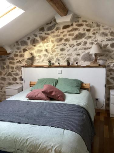 a bedroom with a bed with a stone wall at Maison charmante à Saint-Romain, animaux acceptés. in Saint-Romain