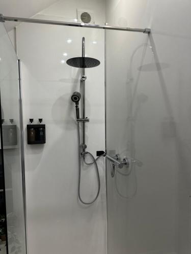a shower with a glass door with a shower head at Hên Stablau - Spacious Pet-Friendly Welsh Retreat by PolkaStays in Llanfihangel-Glyn-Myfyr