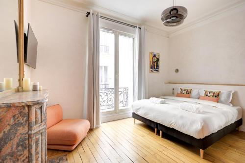 une chambre avec un grand lit et une grande fenêtre dans l'établissement Prestige Marais XL, à Paris