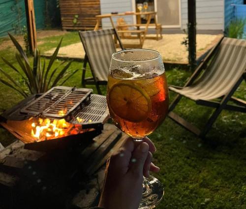 una persona sosteniendo un vaso de cerveza junto a una parrilla en Tiny House Entre Las Sierras Solo Adultos, en Villa Giardino