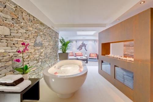 baño con bañera y pared de piedra en Alex Lodge Private Luxury Apartments en Zermatt